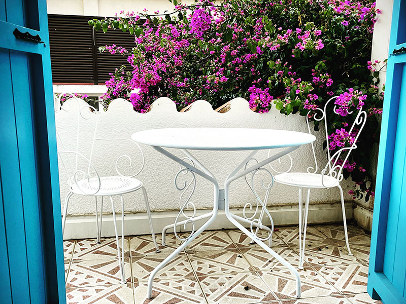 Le petit balcon avec sa table et ses chaises d'extérieur donnant sur le bougainvillet